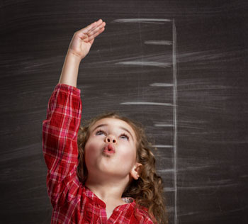 Little girl measuring her height on blackboard